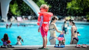 Ein kleines Kind steht mit Schwimmlernweste am Beckenrand im Freibad (Foto: IMAGO / Funke Foto Services)