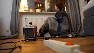 Ein Frau sitzt mit einer Decke hinter einem Elektro-Heizlüfter (Foto: picture alliance/dpa | Philipp Schulze)