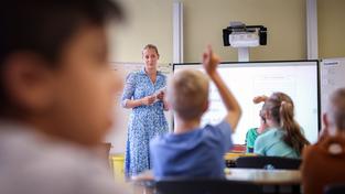 Eine junge Lehrerin steht im Unterricht vor einer Klasse (Foto: picture alliance/dpa | Ronny Hartmann)
