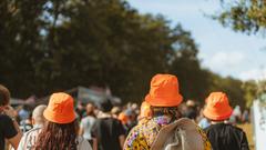 Drei Personen mit orangenen Hüten laufen in einer Menge. (Foto: MXM Photo)