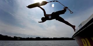 Ein Rettungsschwimmer der DLRG springt von einem Bott in bei einer Übung in einen See. (Foto: dpa)