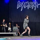 Eine Frau singt, im Hintergrund ist die Band und der Schriftzug "Damona" zu sehen. (Foto: Dirk Guldner)