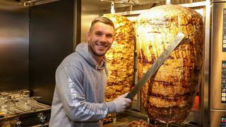 Podolski steht mit einem Messer in der hand vor einem Dönerspieß. (Foto: IMAGO / Eibner)